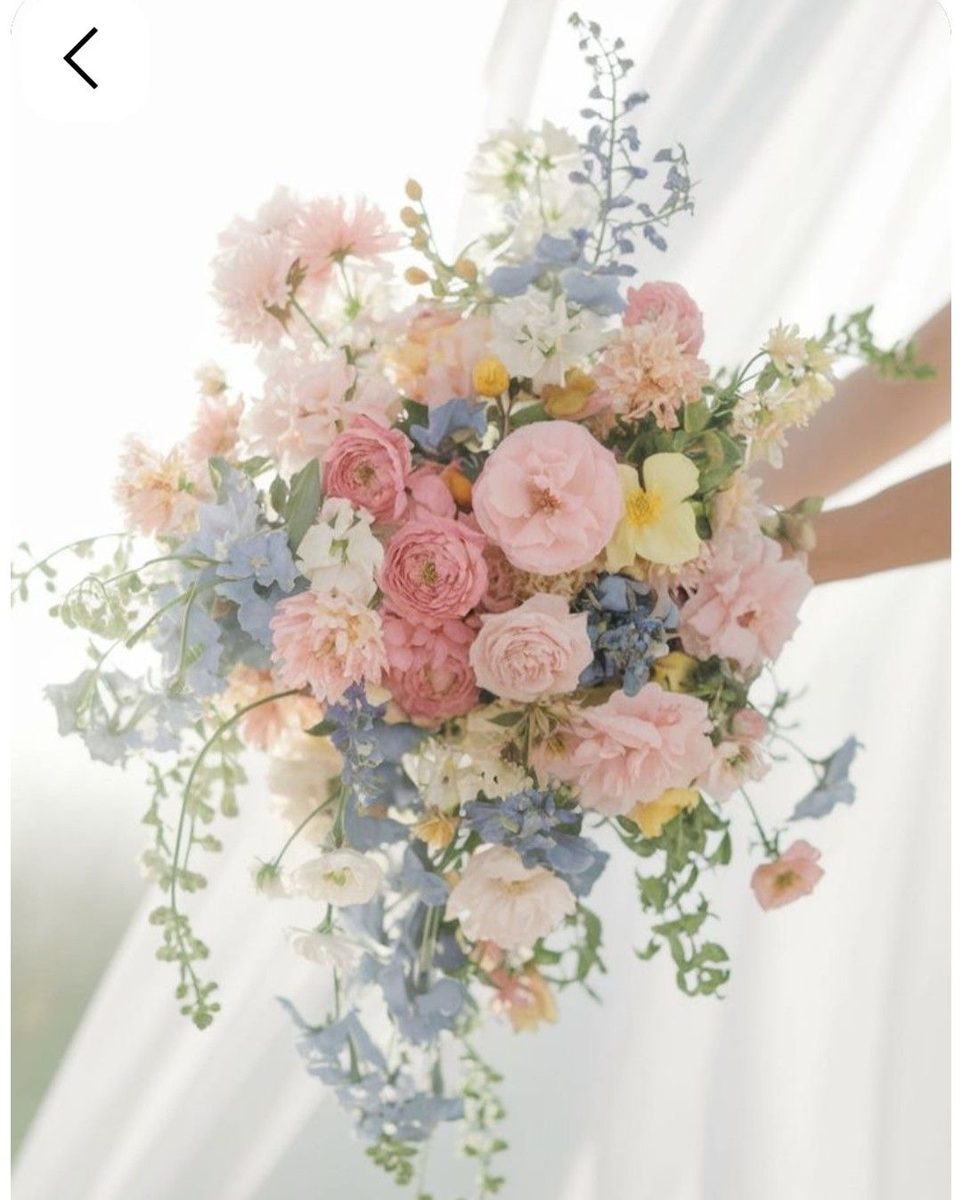 Bouquet aux tons pastel : rose, bleu ciel, jaune pâle et feuillage.