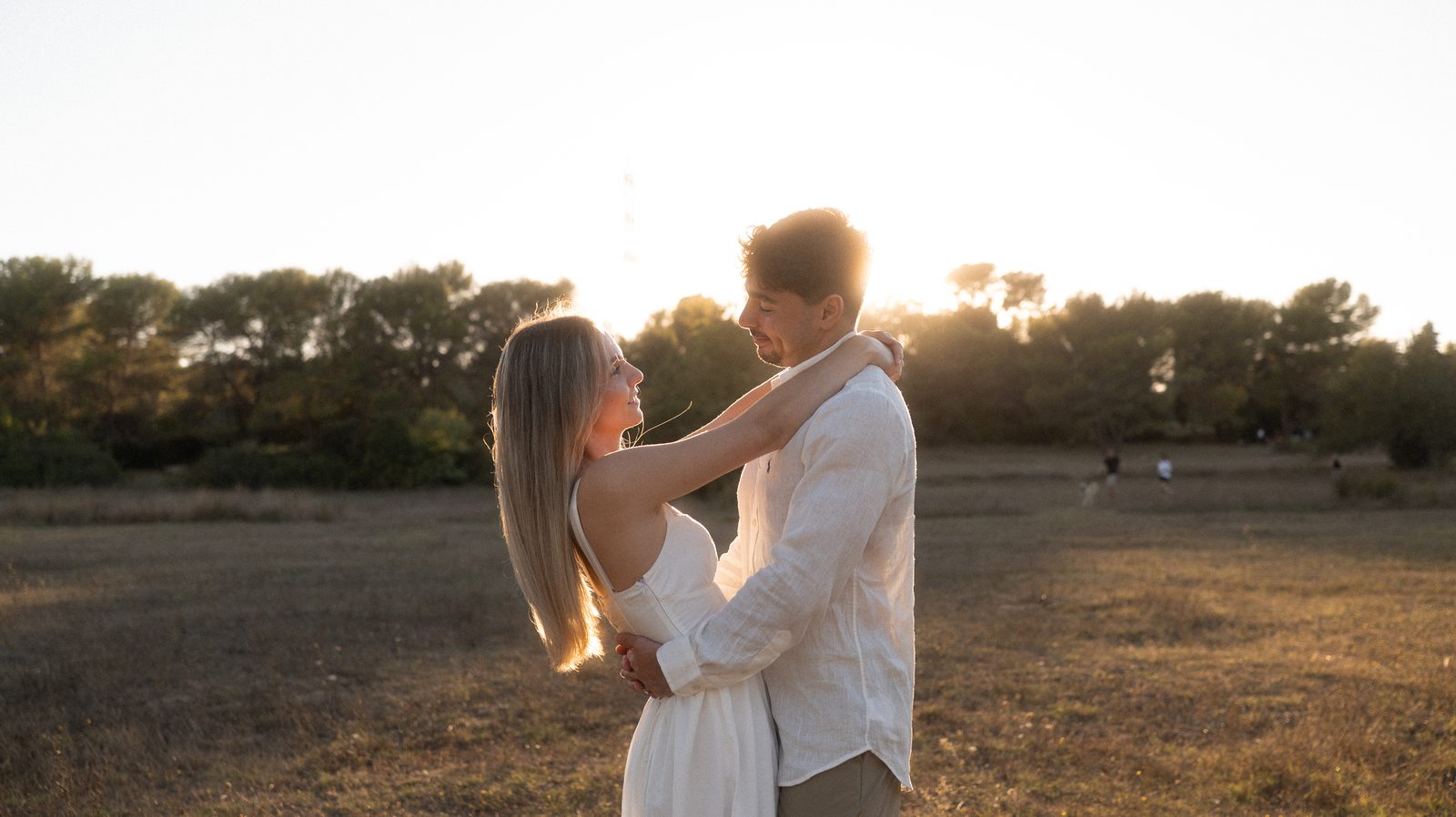 Manon et Benjamin enlacés face au soleil couchant.