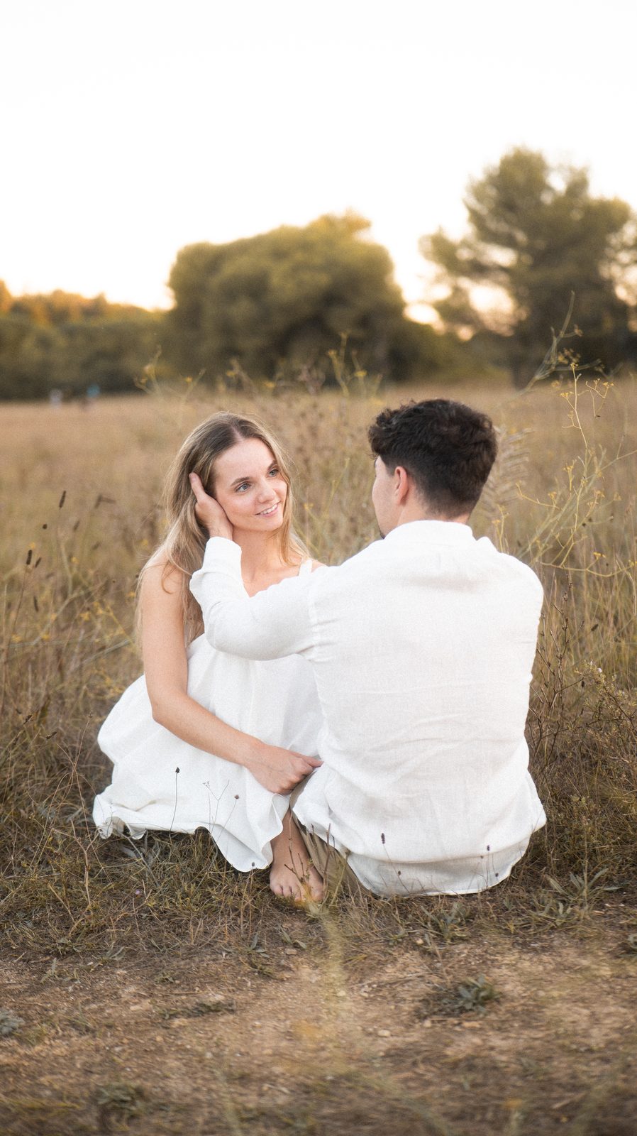 Manon et Benjamin assis dans les herbes sèches, au soleil couchant.